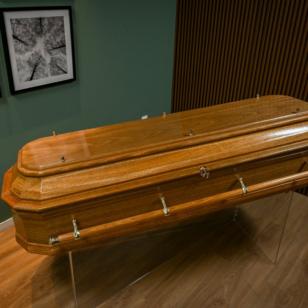 A wooden casket sitting on top of a hard wood floor