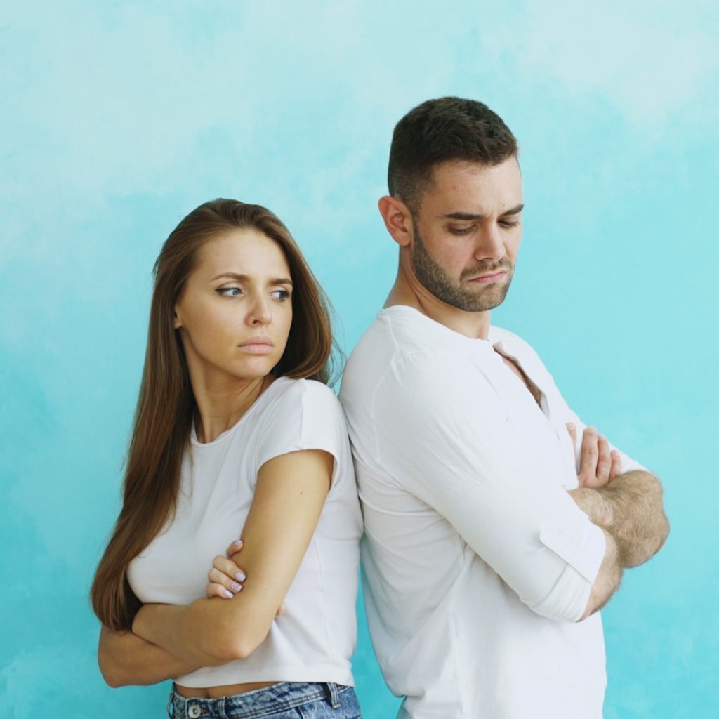 Couple standing back to back with arms crossed