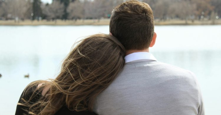 Man and woman sitting by the water