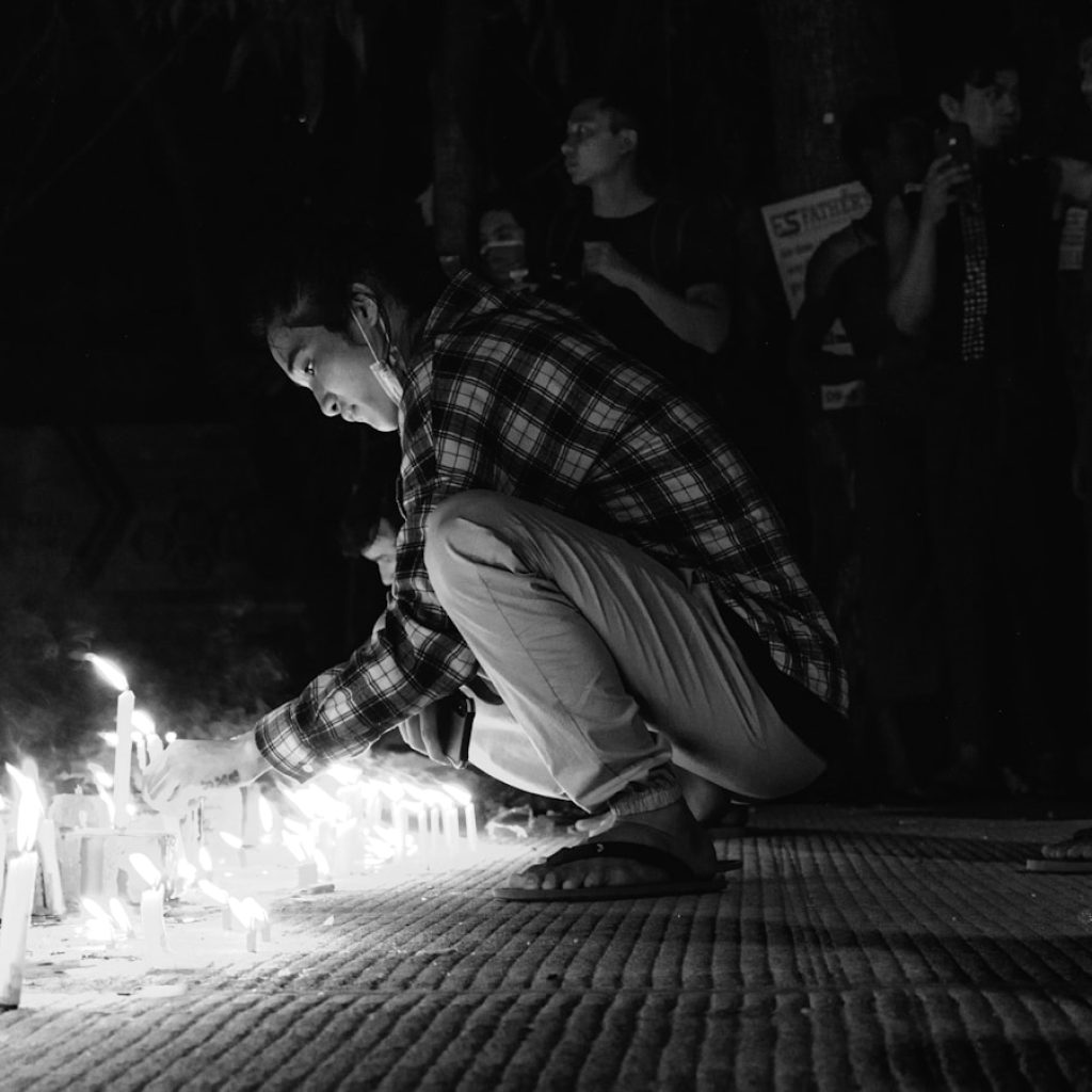 man in plaid shirt and pants sitting on floor with lighted candles