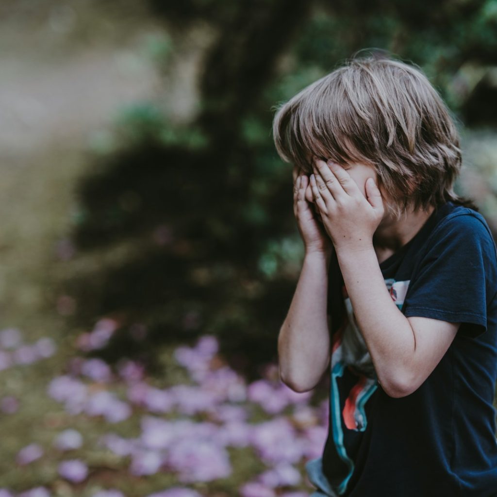 boy covering his face while standing