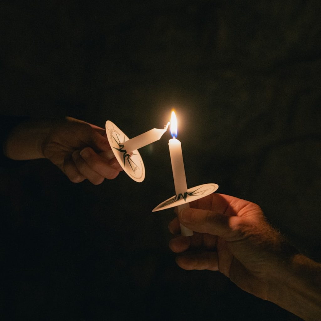 two people holding a candle in their hands