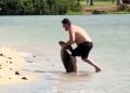 Screengrab from video of man posing with sea turtle