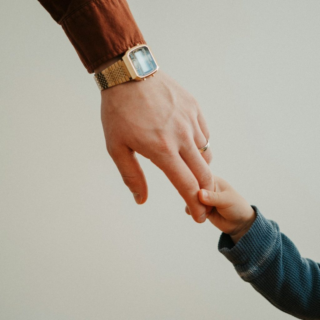 a person holding the hand of a child