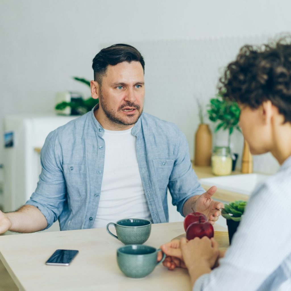 a man sitting at a table talking to a woman