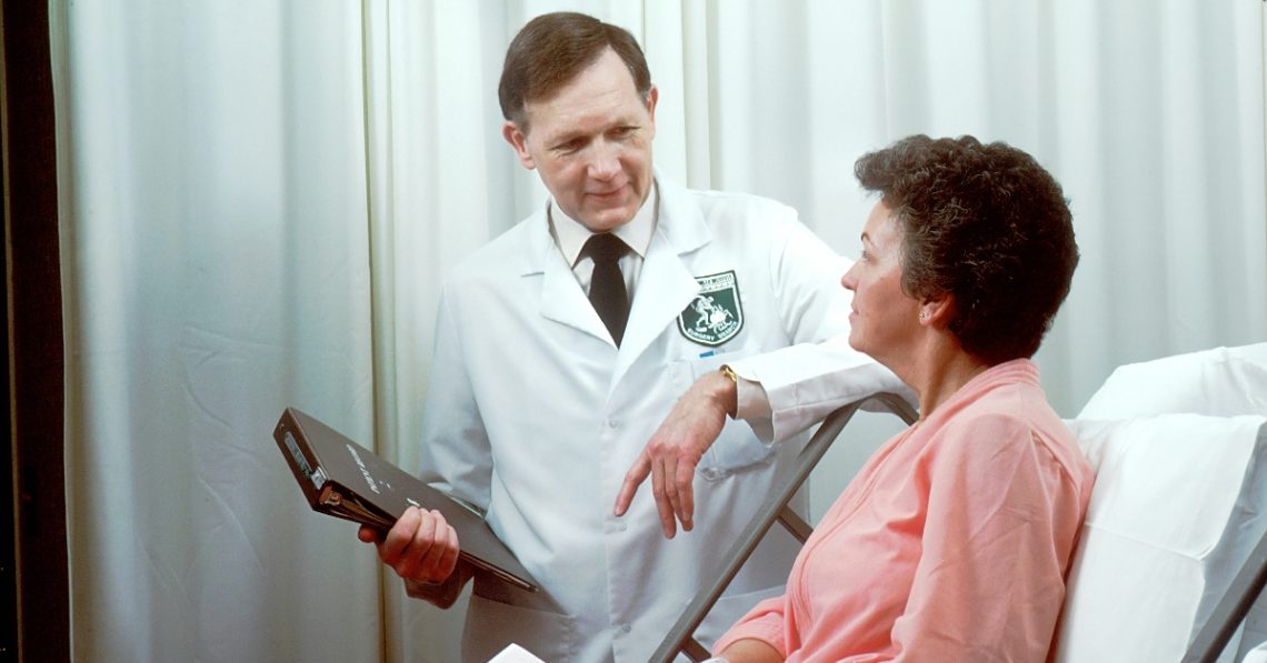 Woman in hospital bed with doctor beside her