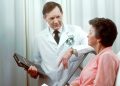 Woman in hospital bed with doctor beside her