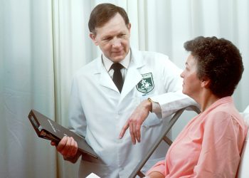 Woman in hospital bed with doctor beside her