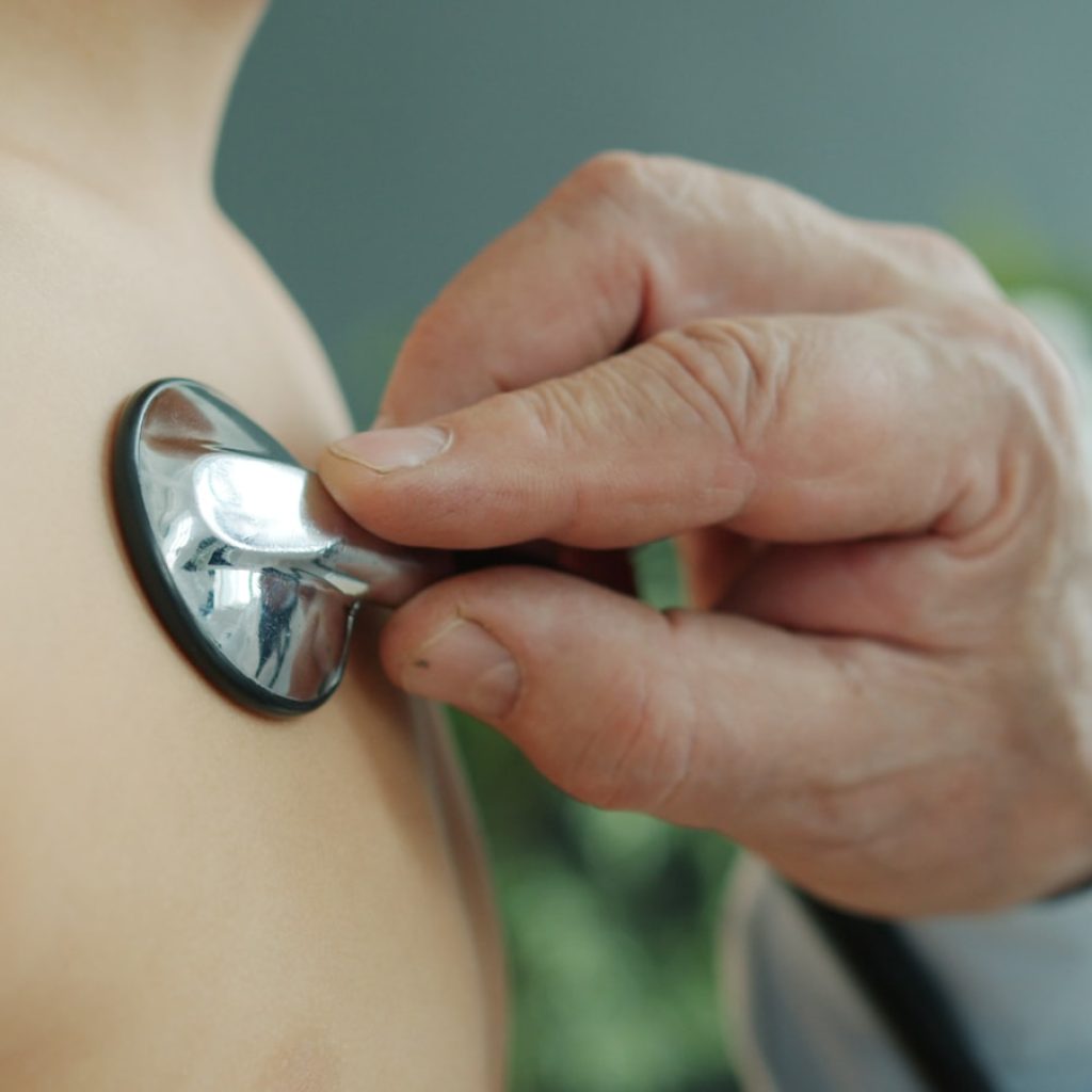 Doctor using stethoscope to examine patient's chest